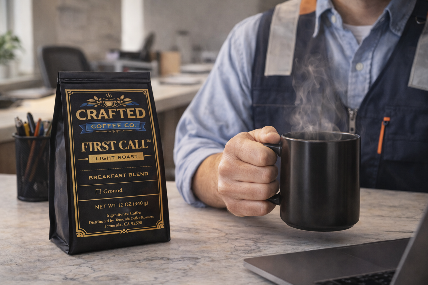 Person holding mug of First Call breakfast blend light roast coffee with bag in background on desk in work environment